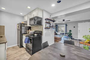 Kitchen featuring black appliances, light hardwood / wood-style floors, backsplash, white cabinetry, and ceiling fan