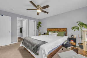 Bedroom with ensuite bathroom, carpet floors, and ceiling fan