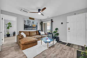 Living room featuring light hardwood / wood-style floors, an AC wall unit, and ceiling fan