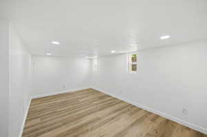 Basement living room with light wood-type flooring and a textured ceiling