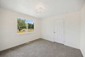 Carpeted spare room featuring a notable chandelier