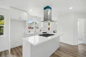 Kitchen with island range hood, sink, a kitchen island, decorative backsplash, and light wood-type flooring