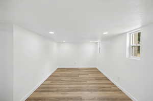 Basement living room with a textured ceiling and light wood-type flooring