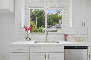 Kitchen featuring sink, dishwasher, decorative backsplash, and white cabinets