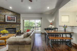 Living room featuring dark hardwood / wood-style floors, ceiling fan, a fireplace, and vaulted ceiling