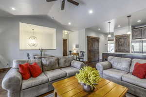 Living room featuring dark hardwood / wood-style flooring, ceiling fan with notable chandelier, lofted ceiling, and sink