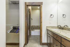 Bathroom with tile patterned flooring, vanity, and a washtub