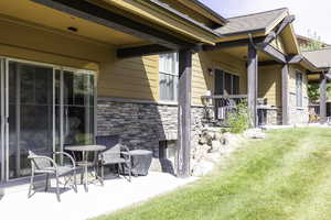 View of property exterior featuring a lawn, a stone fireplace, and a patio