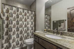 Bathroom with a shower with shower curtain, vanity, and toilet