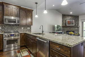 Kitchen with kitchen peninsula, stainless steel appliances, vaulted ceiling, and sink