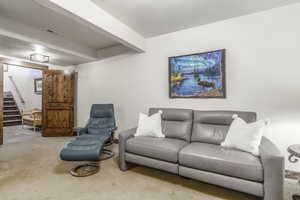 Carpeted living room featuring beam ceiling