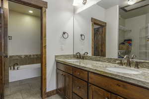 Bathroom featuring tile patterned floors, vanity, and a bath