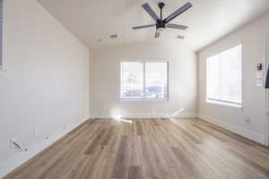 Unfurnished room featuring light hardwood / wood-style flooring, ceiling fan, vaulted ceiling, and a wealth of natural light