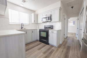 Kitchen with sink, stainless steel appliances, tasteful backsplash, and light hardwood / wood-style flooring