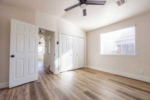 Unfurnished bedroom with light hardwood / wood-style floors, a closet, lofted ceiling, and ceiling fan