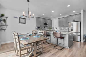 Dining room with sink, a chandelier, and light hardwood / wood-style flooring