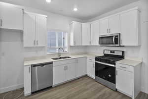 Kitchen featuring sink, appliances with stainless steel finishes, light wood-type flooring, and white cabinets