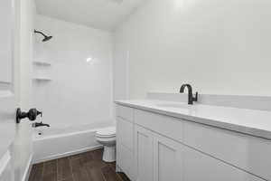 Full bathroom with washtub / shower combination, wood-type flooring, toilet, and vanity