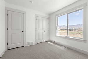 Unfurnished bedroom with a mountain view and light colored carpet