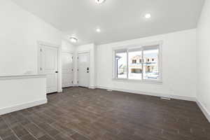 Empty room with lofted ceiling and dark hardwood / wood-style flooring