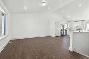 Unfurnished living room with lofted ceiling, sink, and dark wood-type flooring