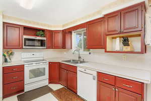 Kitchen featuring sink, light linoleum floors, and white appliances