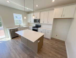 Kitchen featuring sink, light wood-type flooring, stainless steel appliances, and white cabinets