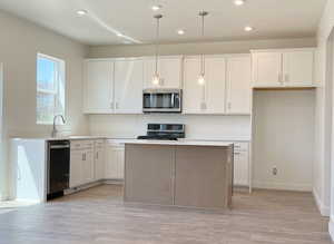 Kitchen featuring a kitchen island, appliances with stainless steel finishes, white cabinets, and light hardwood / wood-style floors