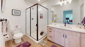 Bathroom with wood-type flooring, toilet, vanity, and an enclosed shower