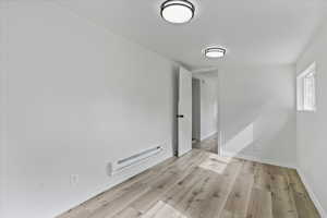 Empty room with a baseboard heating unit and light wood-type flooring