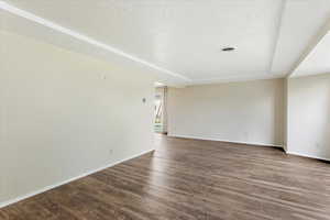 Empty room featuring a textured ceiling, hardwood / wood-style flooring, and a raised ceiling