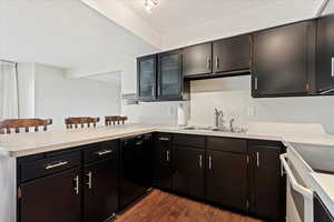 Kitchen featuring a textured ceiling, kitchen peninsula, dishwasher, dark hardwood / wood-style floors, and sink