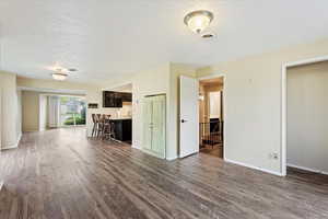 Unfurnished living room featuring a textured ceiling and dark hardwood / wood-style floors