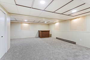 Basement featuring carpet floors, baseboard heating, and a drop ceiling