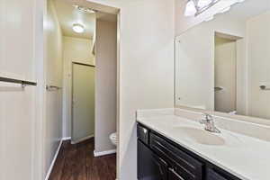 Bathroom with hardwood / wood-style flooring, toilet, and vanity