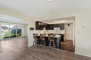 Kitchen with white electric stove, track lighting, kitchen peninsula, a textured ceiling, and dark hardwood / wood-style flooring