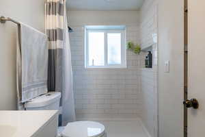 Bathroom featuring vanity, toilet, and curtained shower