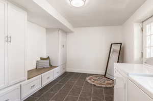 Laundry area featuring separate washer and dryer and dark tile patterned flooring