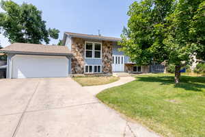 Raised ranch featuring a garage and a front lawn