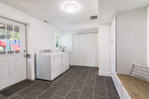 Washroom featuring washer and clothes dryer, dark tile patterned floors, and a wealth of natural light