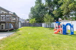 View of yard featuring a deck, a shed, and a playground