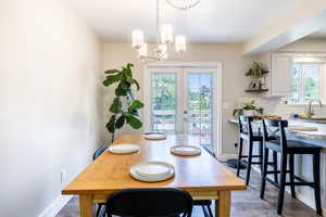 Dining room featuring an inviting chandelier, sink, french doors, and wood-type flooring