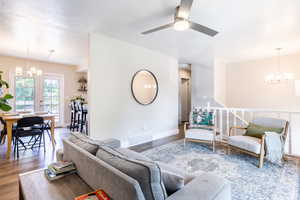 Living room featuring french doors, ceiling fan with notable chandelier, and wood-type flooring