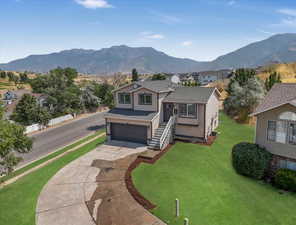 View of front facade with a garage, a mountain view, and a front lawn *This photo has been VIRUTALLY updated to show yard potential*