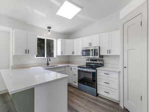 Kitchen with sink, appliances, wood-style flooring, and white cabinets