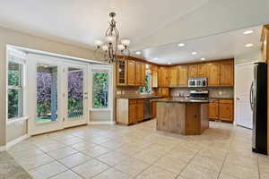 Kitchen with decorative backsplash, stainless steel appliances, decorative light fixtures, and a center island