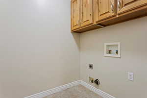 Clothes washing area with cabinets, hookup for an electric dryer, washer hookup, and light tile patterned floors