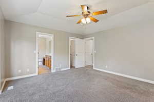 Unfurnished bedroom with ensuite bathroom, ceiling fan, lofted ceiling, and light colored carpet