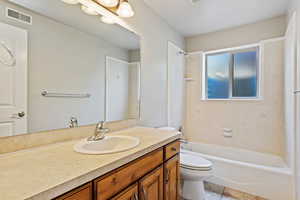 Full bathroom with tile patterned floors, toilet, vanity, and tiled shower / bath