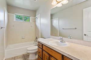 Full bathroom with tile patterned flooring, toilet, vanity, and tiled shower / bath